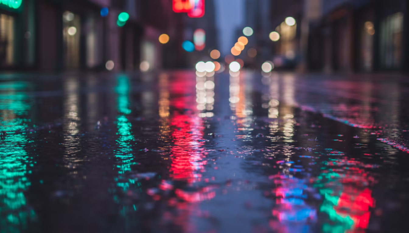 Neon signs reflected in rain-soaked pavement — the iconic rain-plus-neon photography look, doubled colors on wet surface